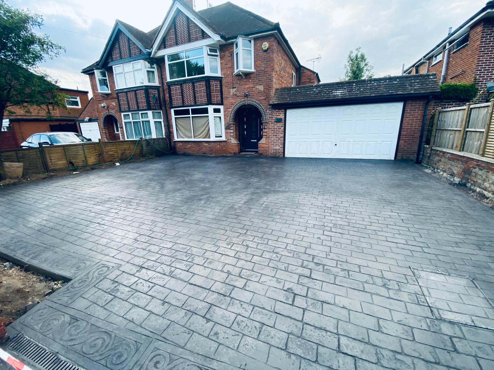 Restored frontage with new pattern-imprinted driveway for a Tudor-style home by SIB Construction